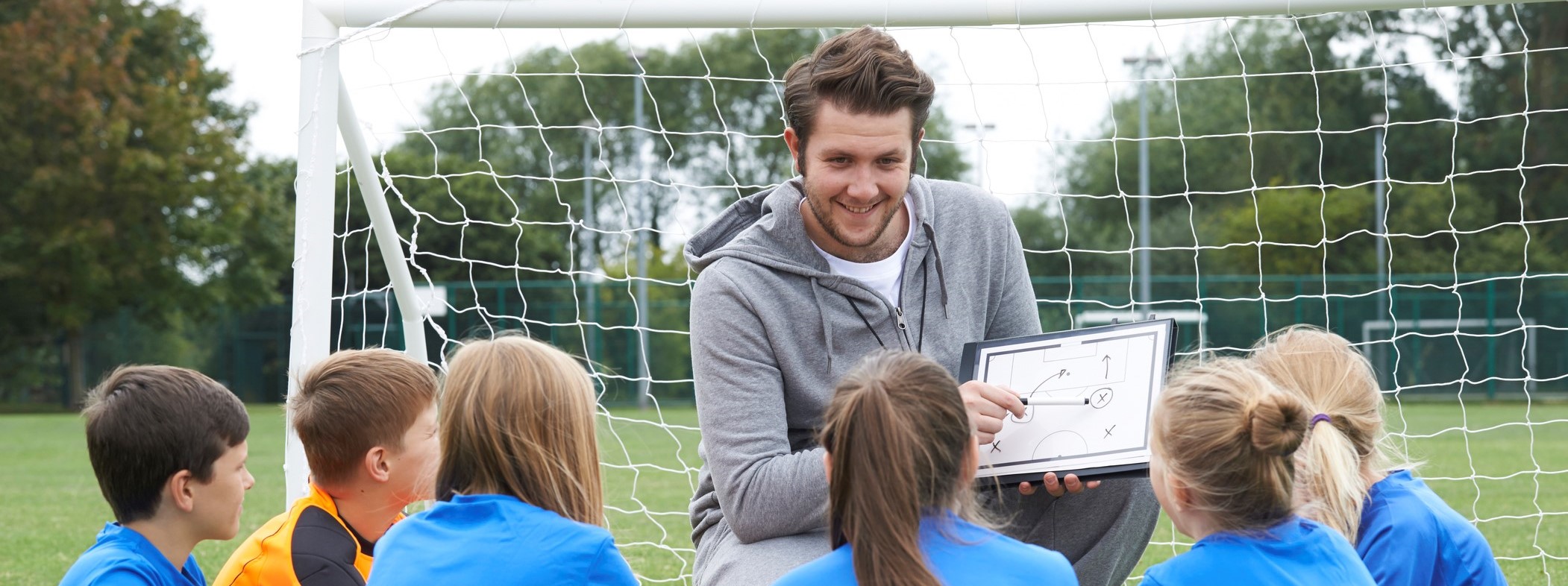 entraîneur qui parle à des jeunes à coté d'une cage de football