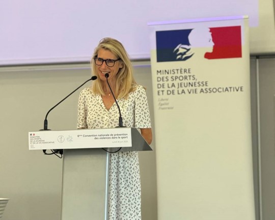 Photo de Marie Barsacq à la convention VSS 2025 en train de parler au pupitre