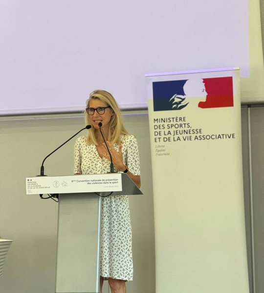 Photo de Marie Barsacq à la convention VSS 2025 en train de parler au pupitre