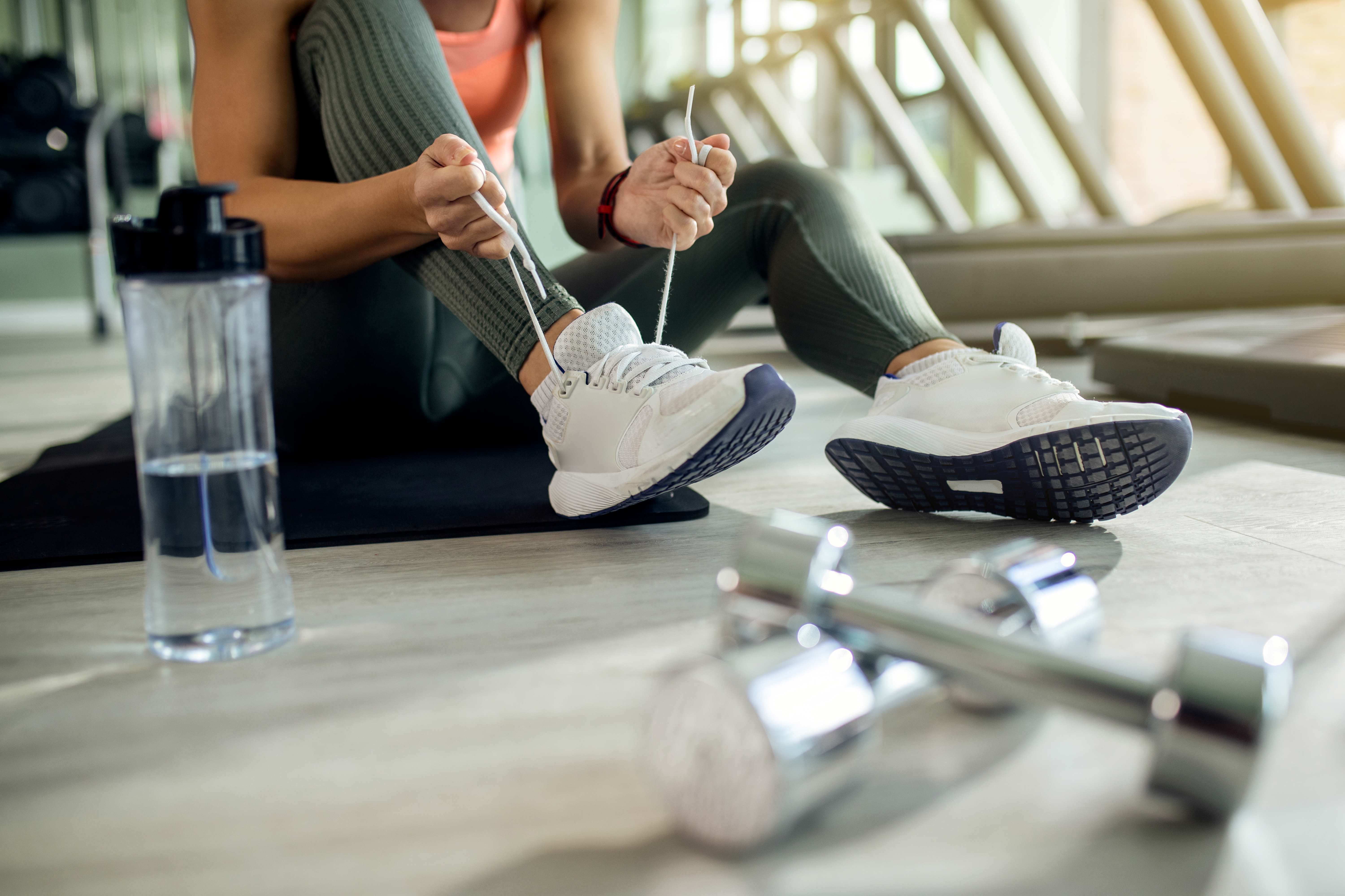 femme-athletique-attachant-une-chaussure-de-sport-au-club-de-sante