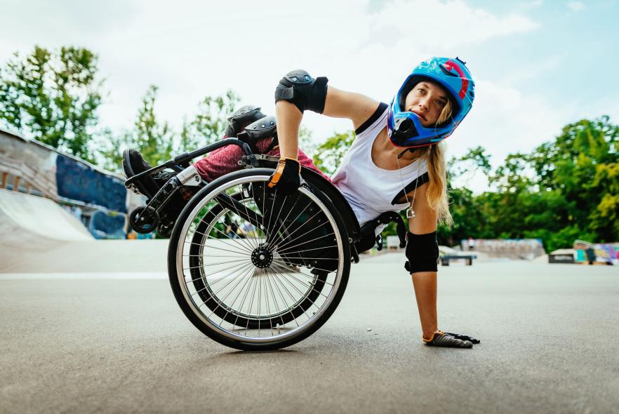 Jeune femme avec un casque et des coudières faisant du sport dans un fauteuil roulant