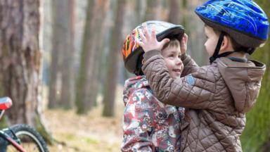 Deux petits garçon avec un casque de vélo sur la tête en forêt.