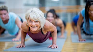 Femme âgée avec d'autres personnes sur un tapis de yoga