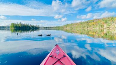 Photo d'un canoë sur un étang reflétant le bleu du ciel et les nuages
