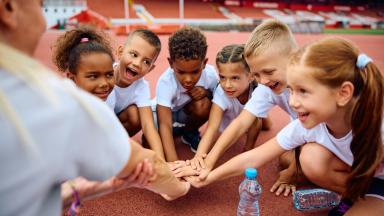 Image avec des filles et des garçons dans un stade sportif avec leur entraîneur