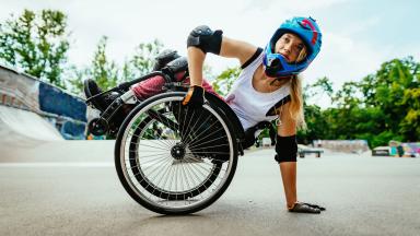Jeune femme avec un casque et des coudières faisant du sport dans un fauteuil roulant
