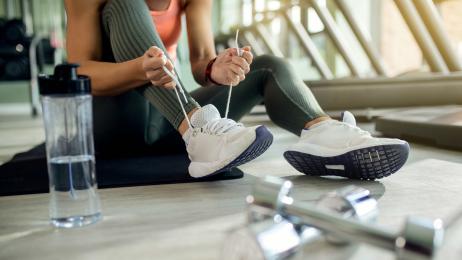 femme-athletique-attachant-une-chaussure-de-sport-au-club-de-sante